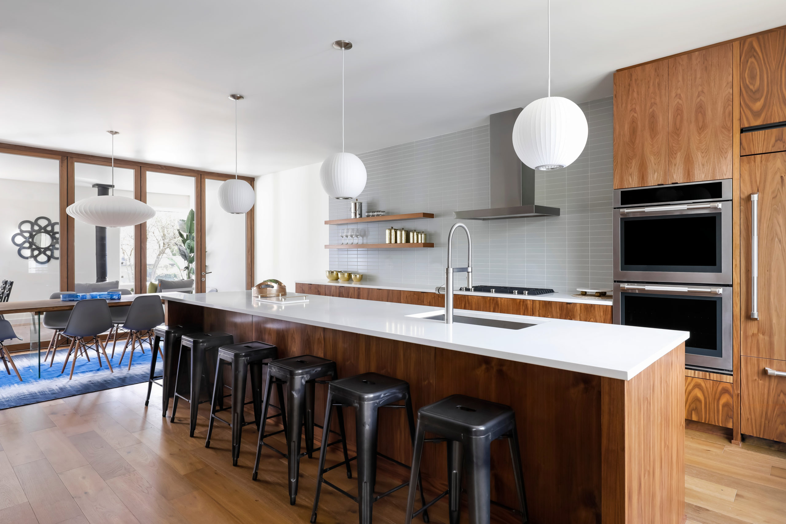 Modern kitchen with black metal bar stools and wooden island with white countertops