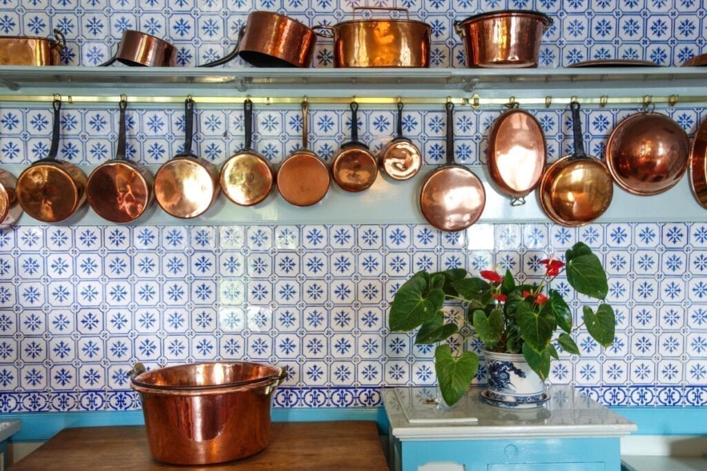 Kitchen with blue tiled backsplash and copper pots and pans