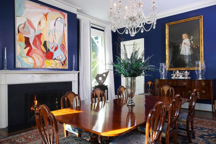 A dining room furnished with a Regency-style table, console, and chairs; Persian rug, abstract artwork; and 