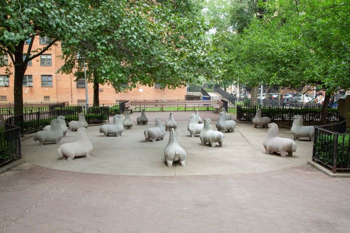 A group of horse statues located under the leafy trees.