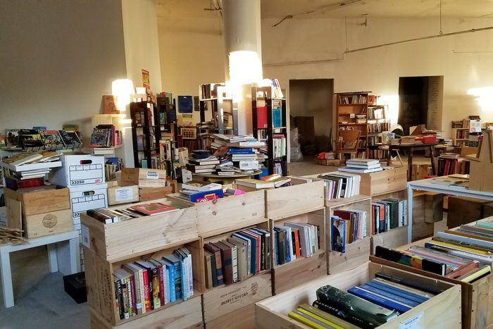 Books in crates and shelves and tables spread across a hall.