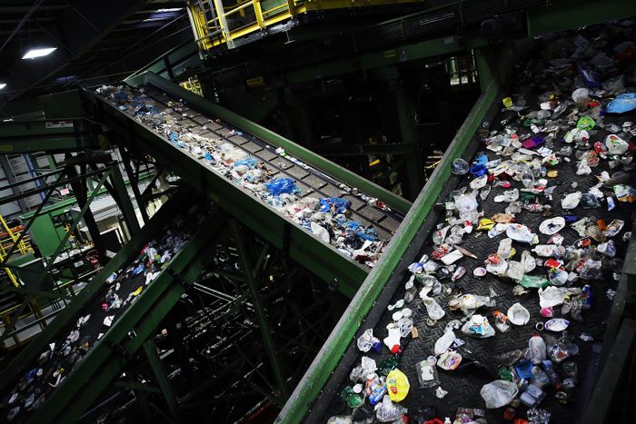 Bouteilles en plastique, canettes, bouteilles en verre sur deux bandes transporteuses entrecroisées.