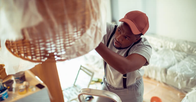 Young man working on the chandelier and painting the house