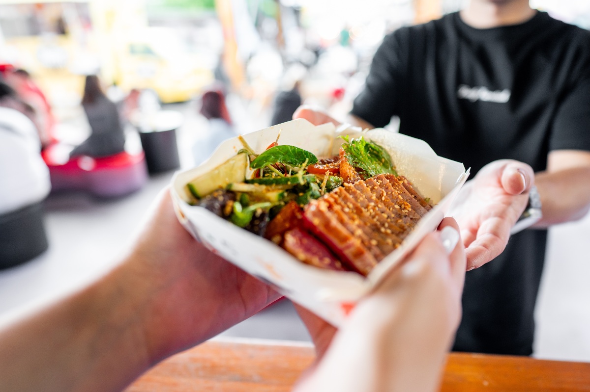 A person gets a plate of food from a food truck.