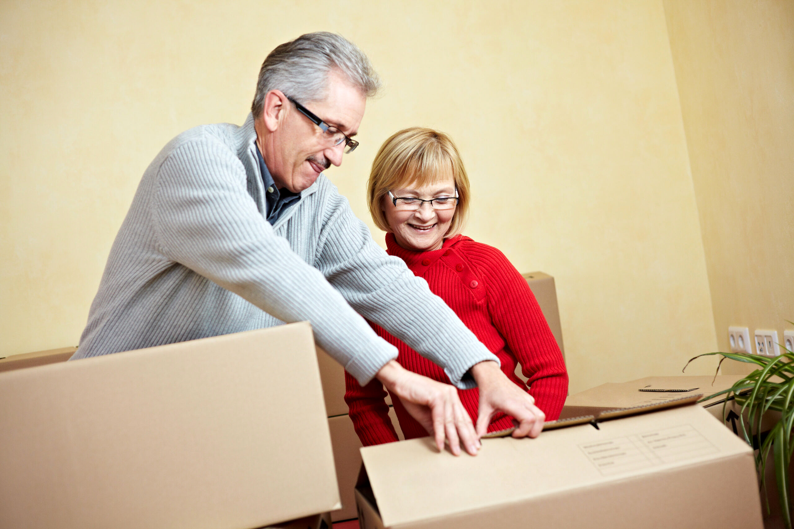 Two happy senior people with many moving boxes