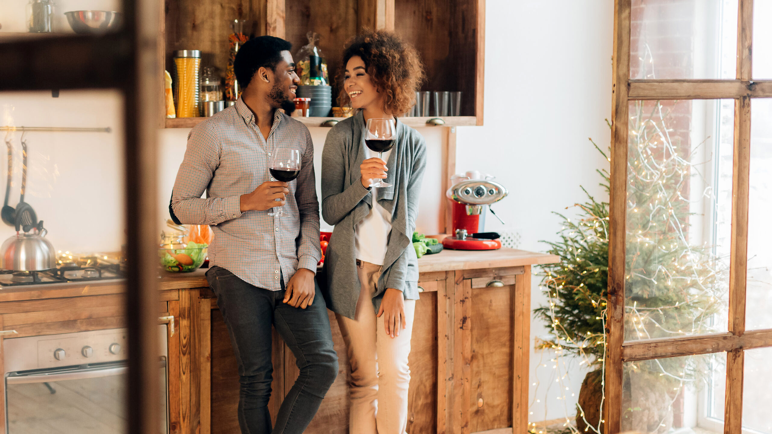 Romance in everyday life. Cheerful african-american man and woman enjoying wine at kitchen, panorama, copy space