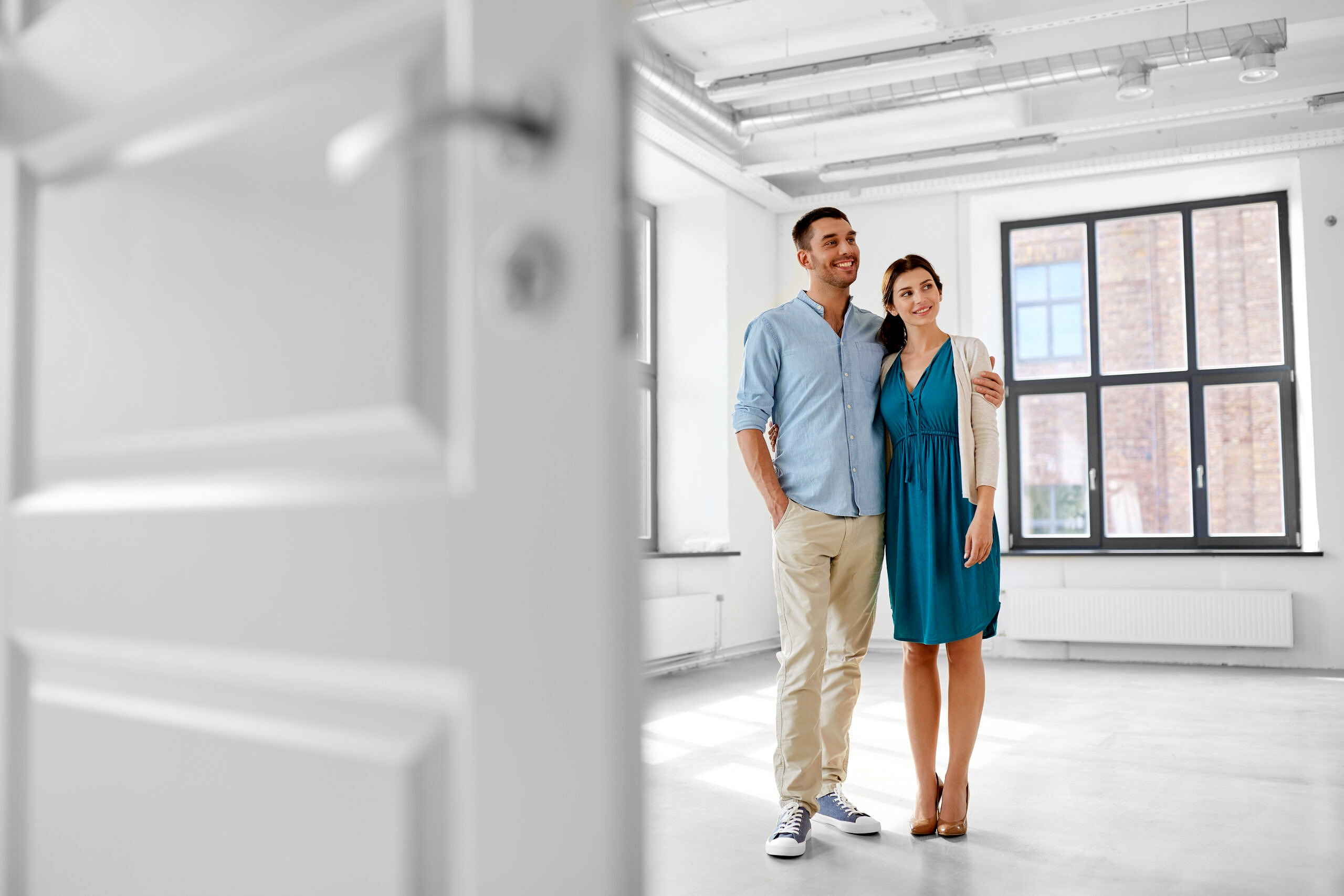 mortgage, people and real estate concept - happy couple hugging at new home