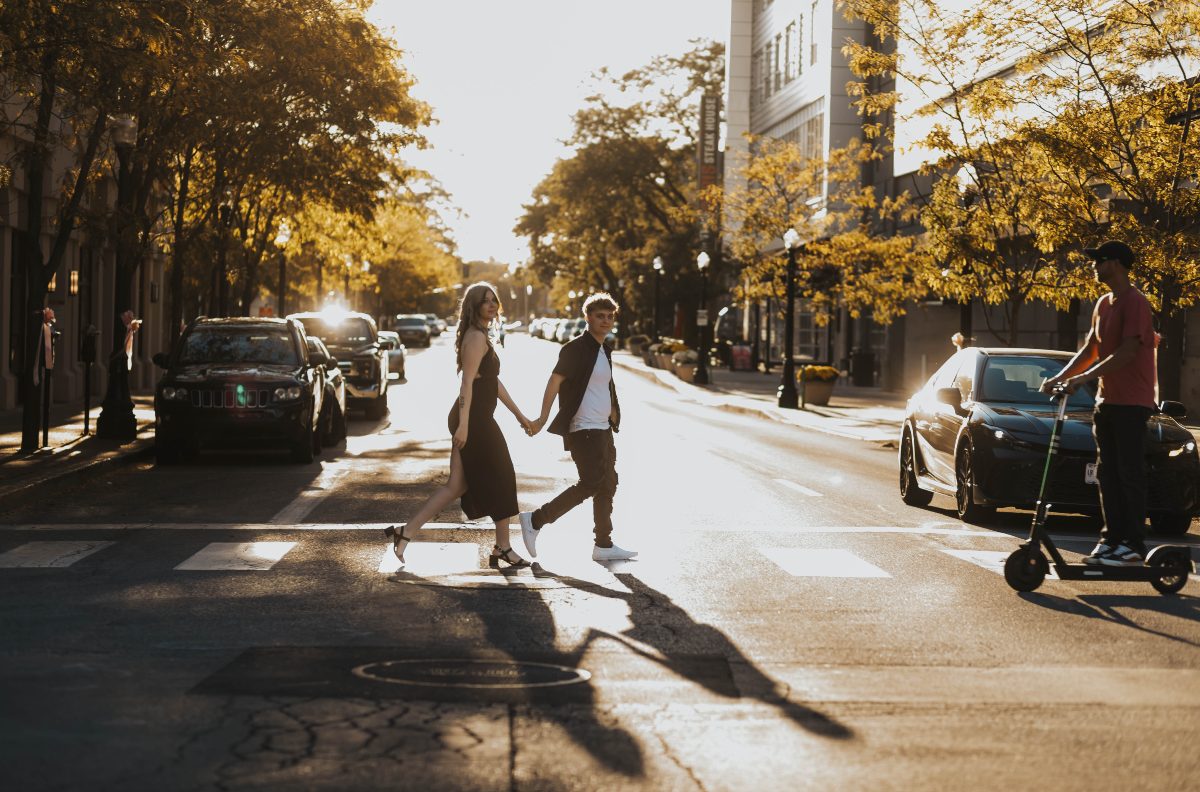 A couple crosses the street on a bright sunny day in Fort Wayne, IN as captured by Real Living Photography.