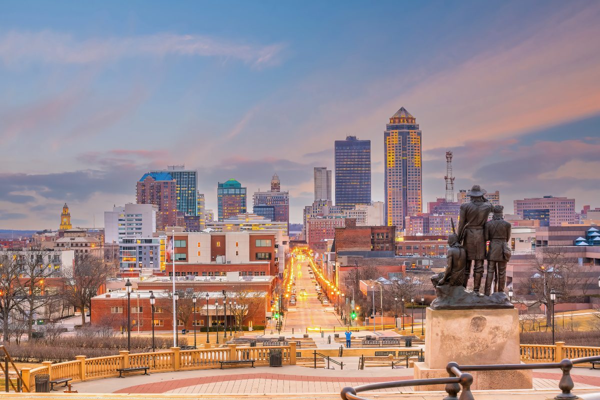 A view of the city of Moines, at dusk when the city lights light up. The lighting is hot and the blue sky darkens with fishing clouds. 