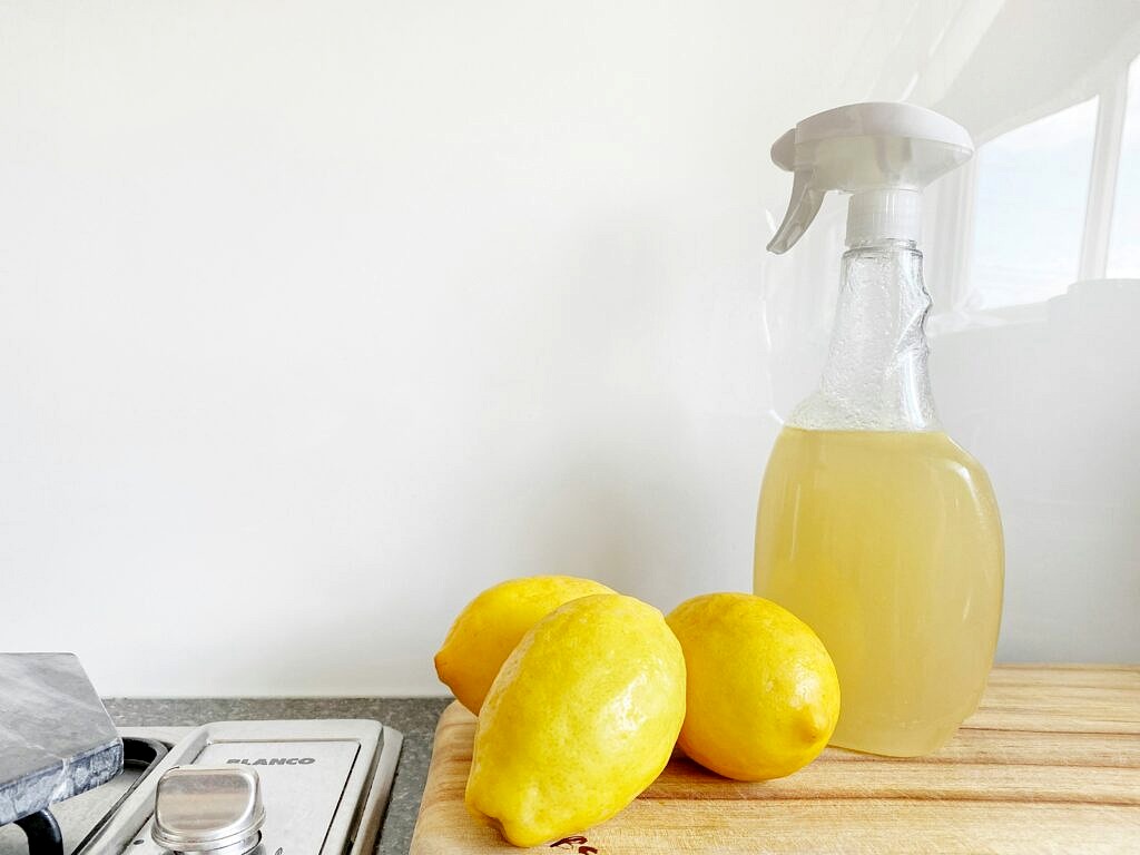 Clean natural in a sprayed bottle next to lemons