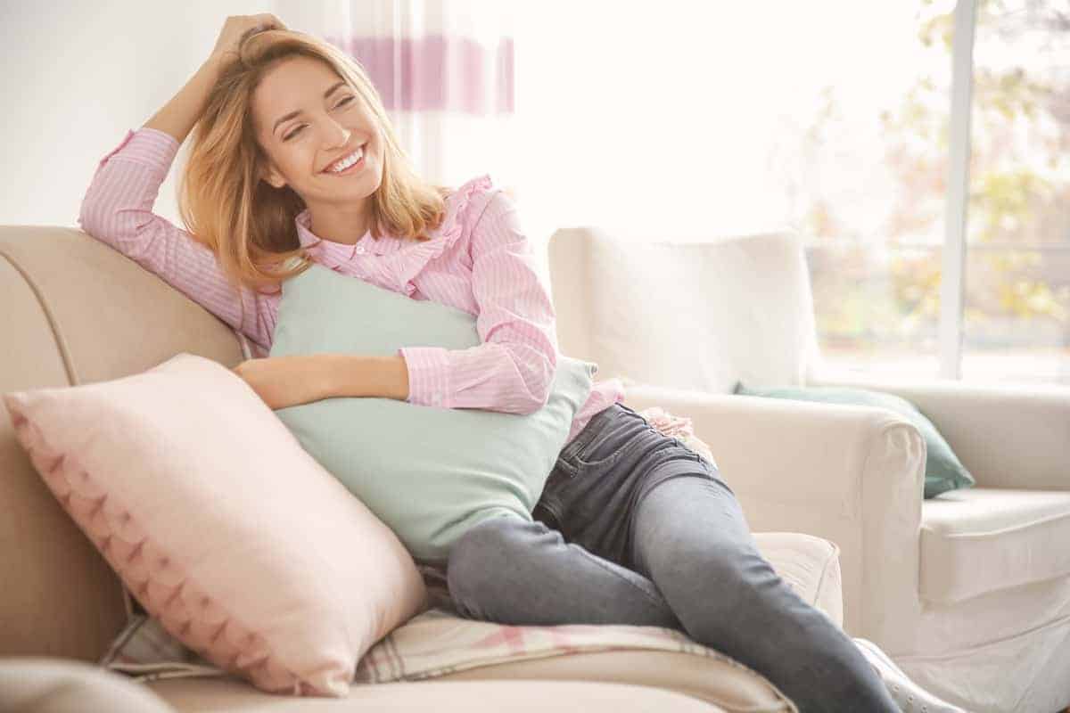 Happy woman sitting on the sofa with pillows